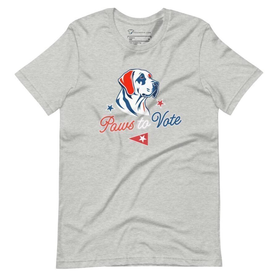 The "Paws to Vote | Elections 2024" unisex t-shirt is a gray tee featuring a dog illustration above the text "Paws to Vote" in red and blue, complemented by red and blue stars and a small red pennant—ideal for showing support during Elections 2024.